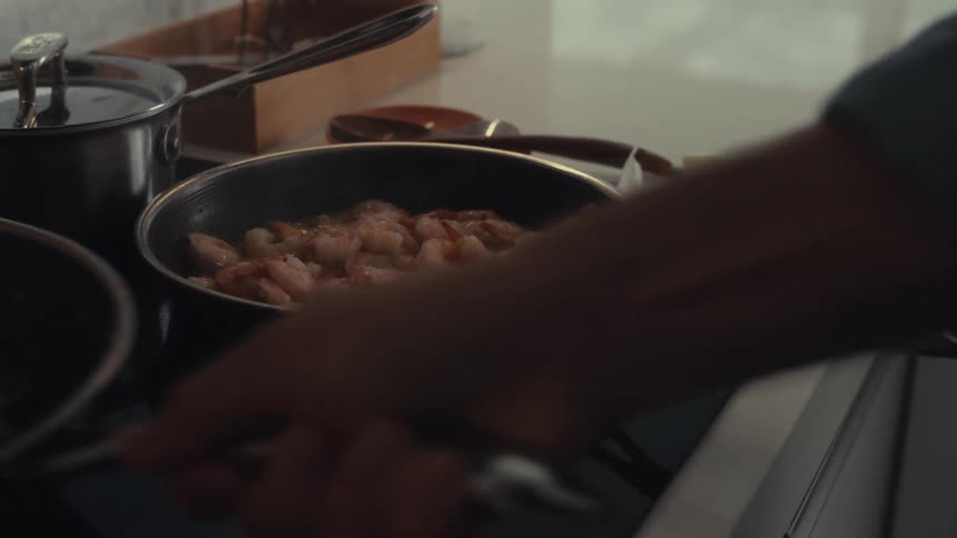 A person is cooking shrimp on the stove