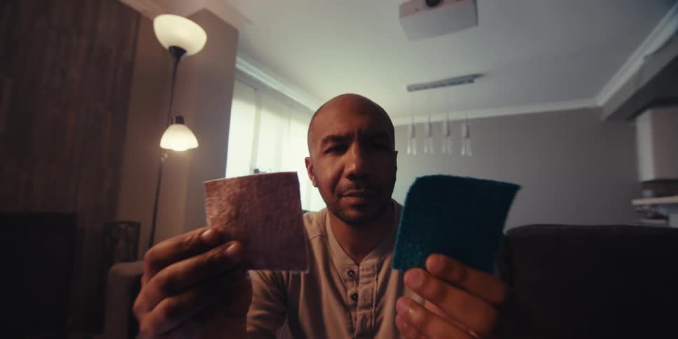 A man holds up two squares and smiles