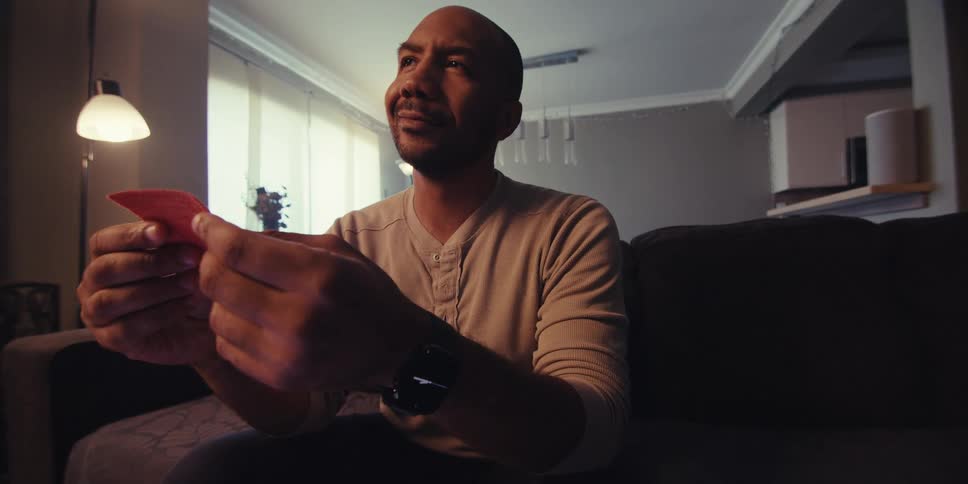 A man smiles while holding up a fabric square