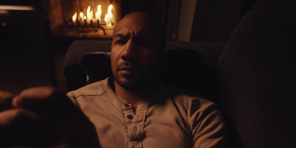 Man concentrates while lying on the couch and viewing a smartphone