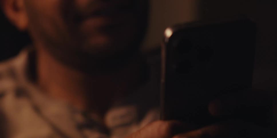 A man is using his cell by the fireplace