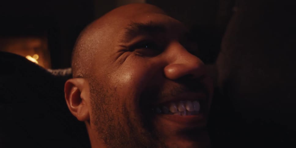 The face of a happy man who is looking at his cell phone while lying on the couch and celebrating