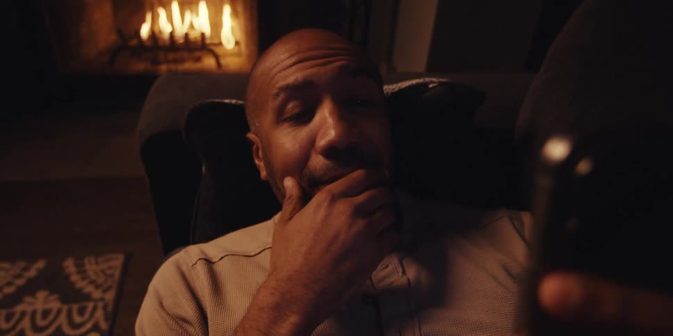 A man is relaxing on the couch and looking at his cell phone
