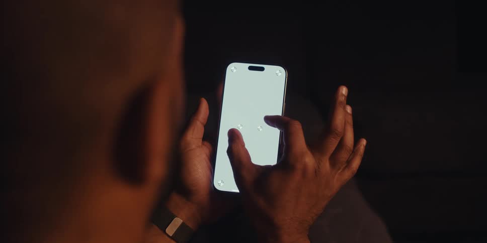 A persons hand moving their fingers on the white screen of a cell phone