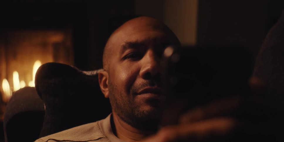 Man lying on a sofa with a fireplace in the background and interacting with a smartphone