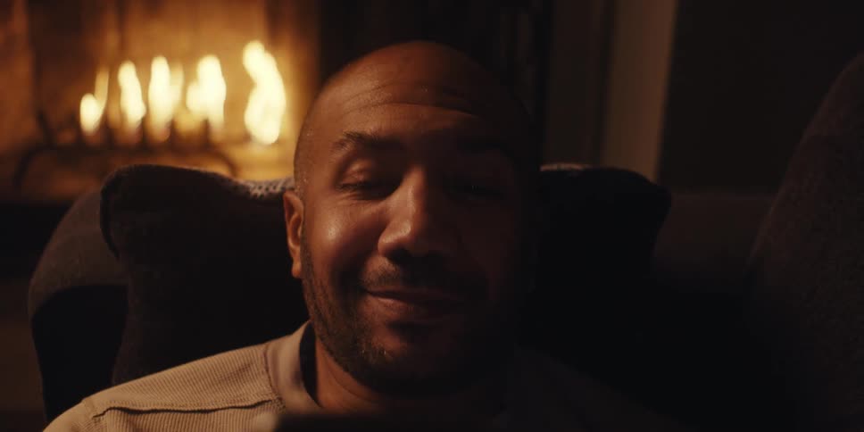 A man uses a cell phone by the fireplace