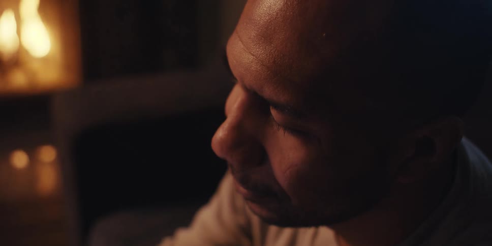 A man is sitting by the fireplace