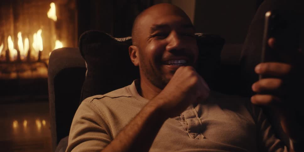 A man cheers while looking at his phone