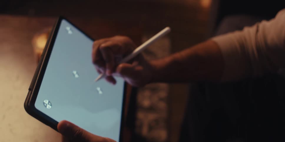 The face of a man who is thoughtful and then he starts drawing on the screen of a tablet using a white pen