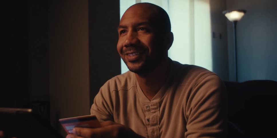 Man who contentedly types his credit card information into the tablet