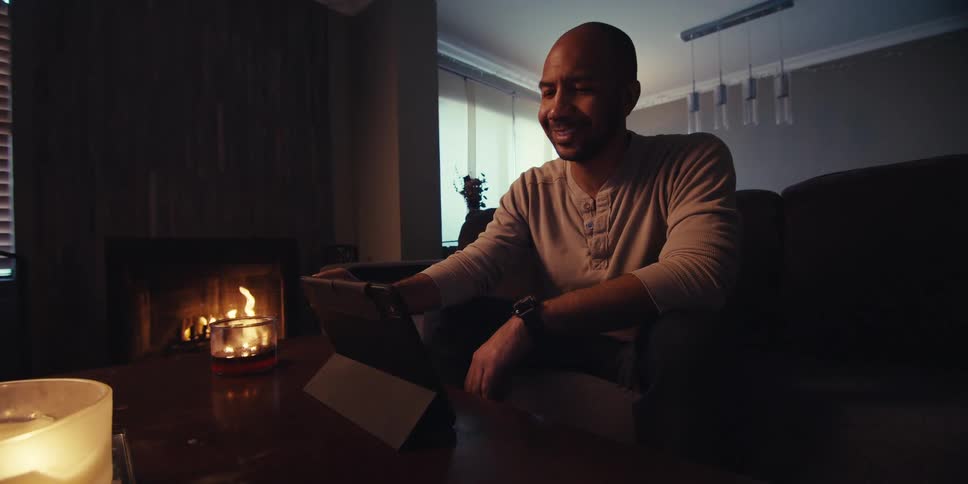 A man taps his tablet by the fireplace