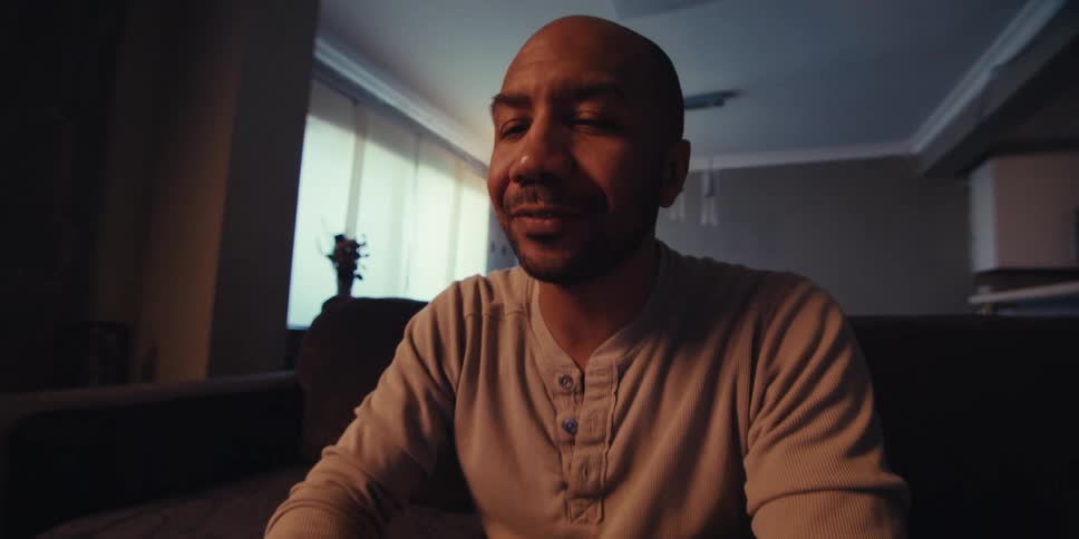 Man sitting on a couch talking to someone gesticulating then seen using a tablet