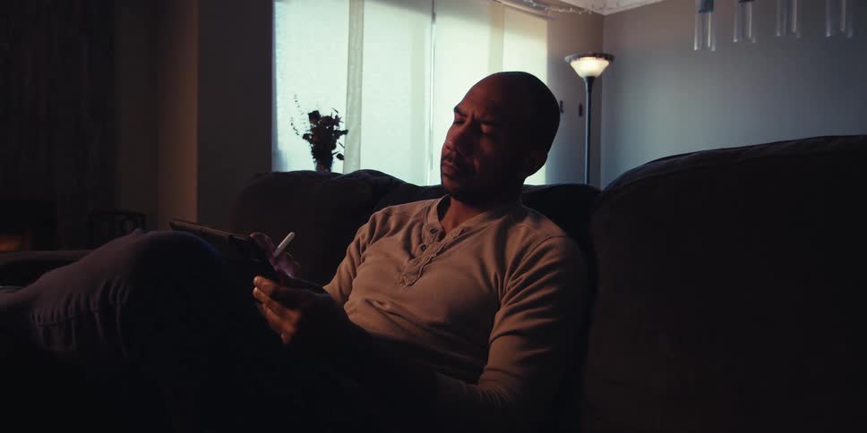 A man is typing on his table as he sits on a couch