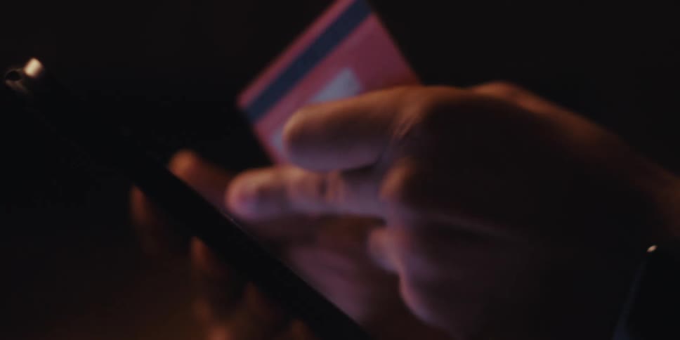 Hand holding a red credit card and typing on a tablet screen