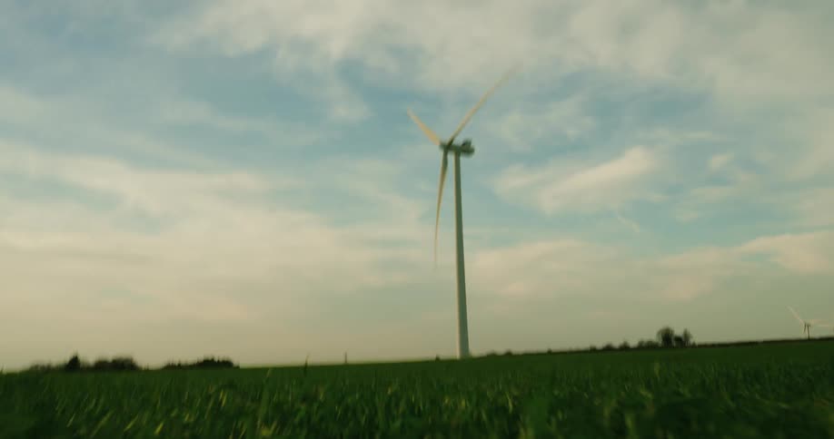 A very tall windmill is slowly spinning