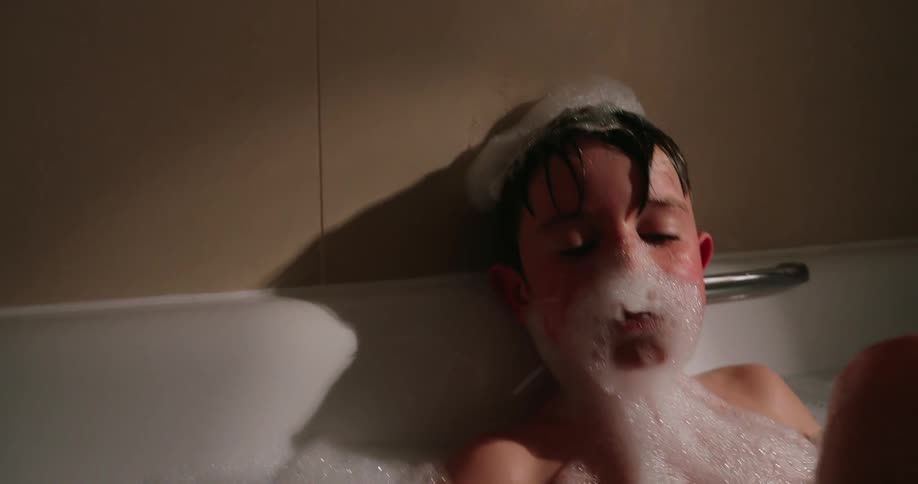 A child is putting bubbles on his face from a bath