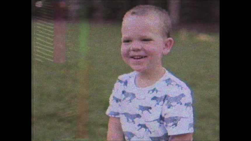 A boy sitting on a grassy field smile for the camera
