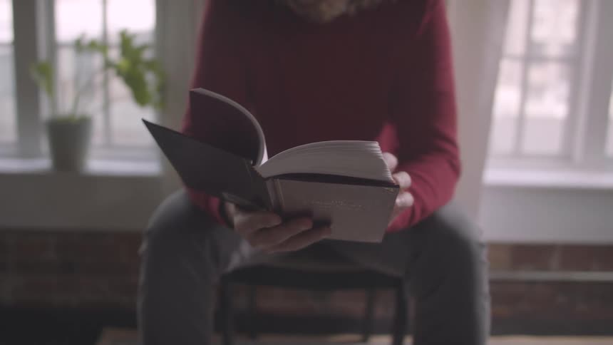 Elderly man reading a book while sitting