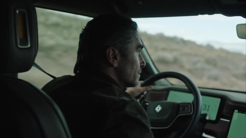 A man driving his car through the grasslands while looking for something