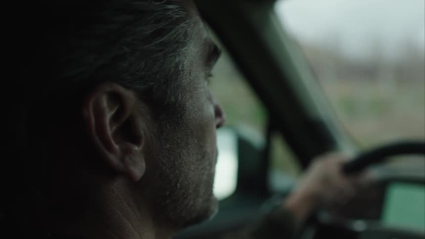 A man driving a car is looking for something on his right side