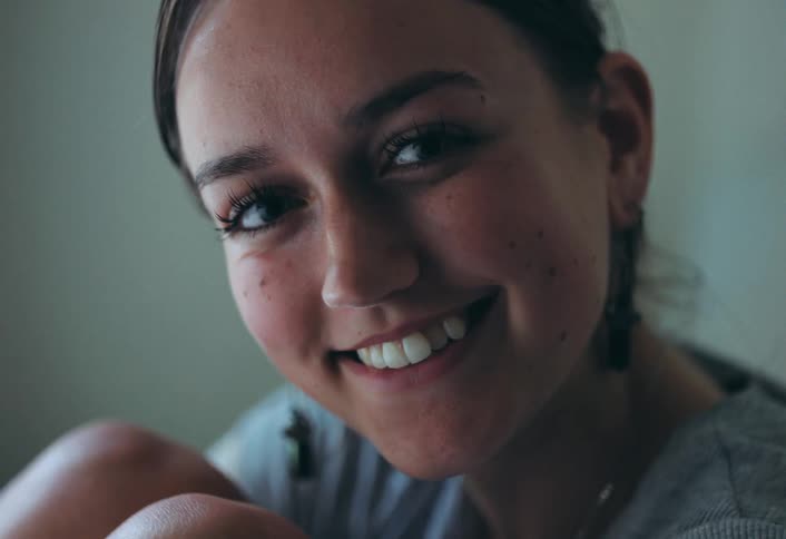 Woman sitting with her knees drawn up to her chest smiles