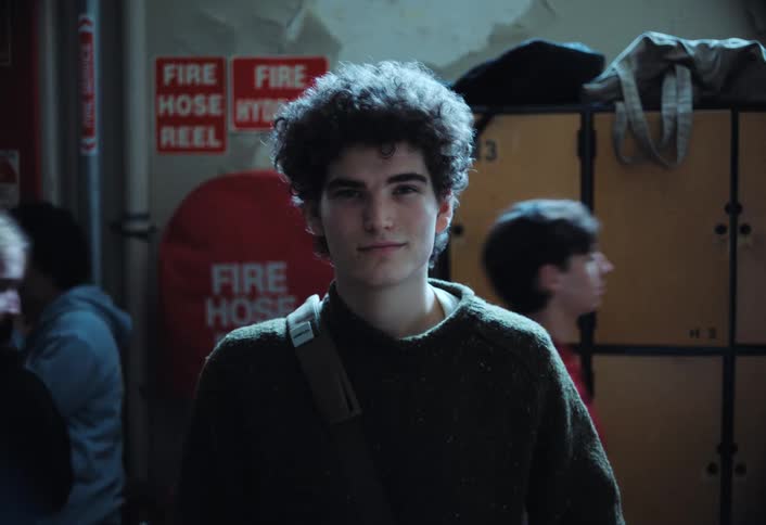A student is standing in the hallway in front of lockers