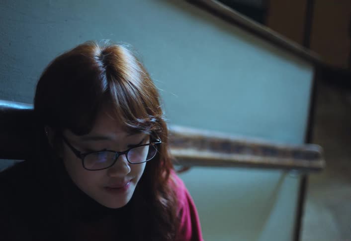 A footage of an asian lady siting by a corner