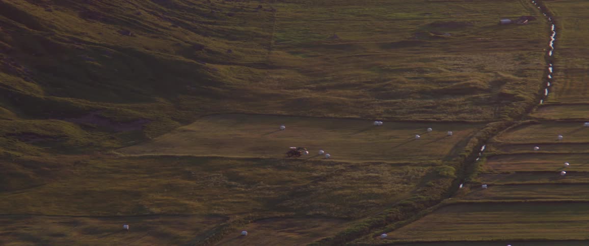 Landscape seen from a distance of a field worked by a tractor