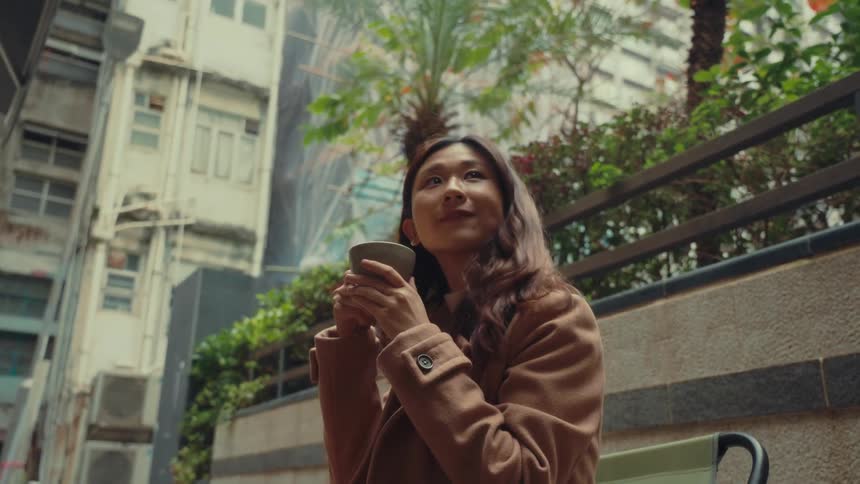 A woman drinks coffee outside in the city