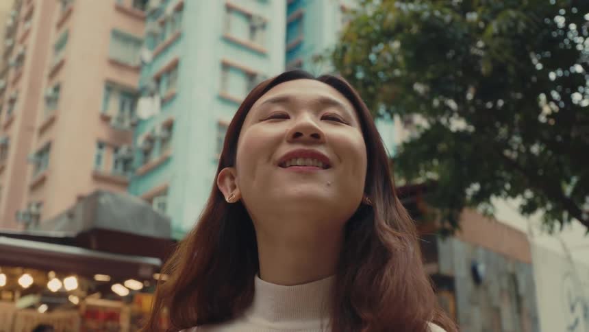 A footage of an asian girl looking around the neighborhood with a smile