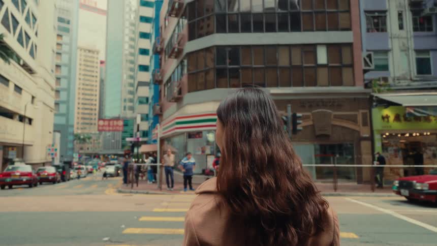 A woman waits to cross the street in the city