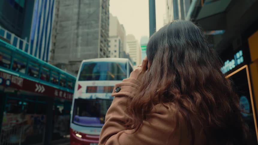 A footage of a lady standing and taking a photo at the bus terminal