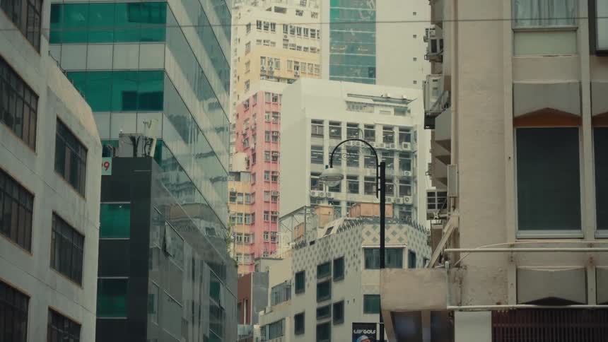 A handheld shot shows a dense urban hong kong landscape where towering skyscrapers featuring an mixed style of architectural designs reach skyward in a display of metropolitan
