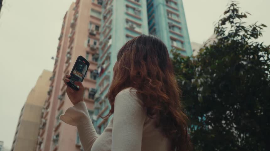 Happy female tourist recording surroundings on cell phone in metropolitan area