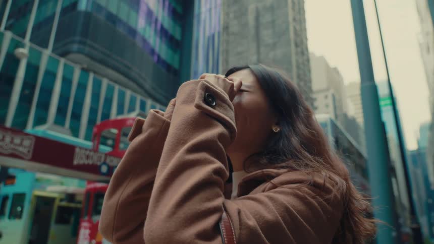 Woman using an analog camera while standing in the middle of an urban city