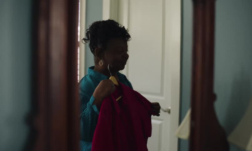 A woman holds a blouse up to the mirror