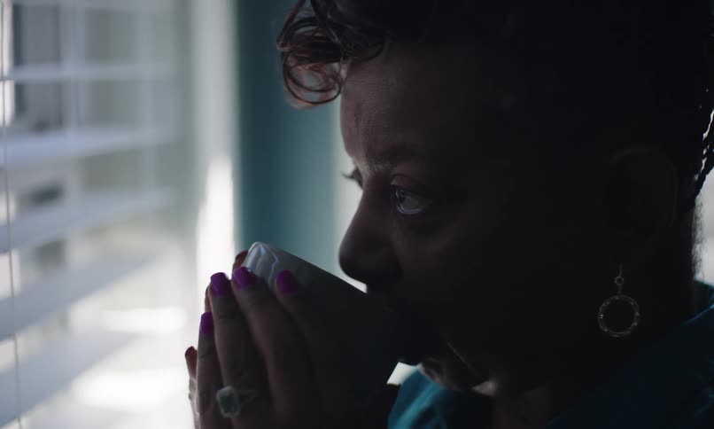 A woman nods her head while drinking coffee