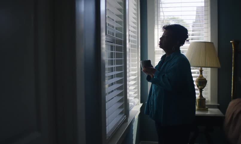 The woman drinks coffee and looks out the window