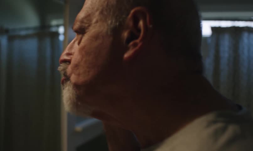 Elderly man brushing his teeth while looking in the mirror