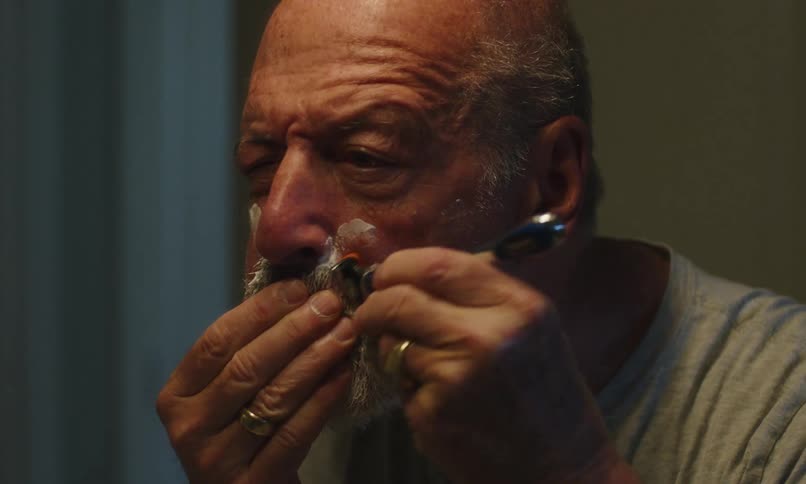 Man shaving himself looking in the mirror