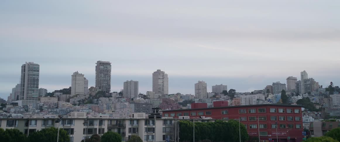 The san franciscos cityscape is on view showcasing its recognizable tall buildings and dense urban design spreading beneath a wide pale grey and cloudy expanse