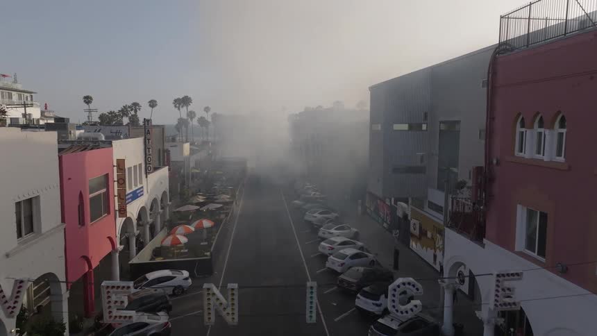 An aerial view of a street in venice usa showing smoke billowing at the end of the street during the morning