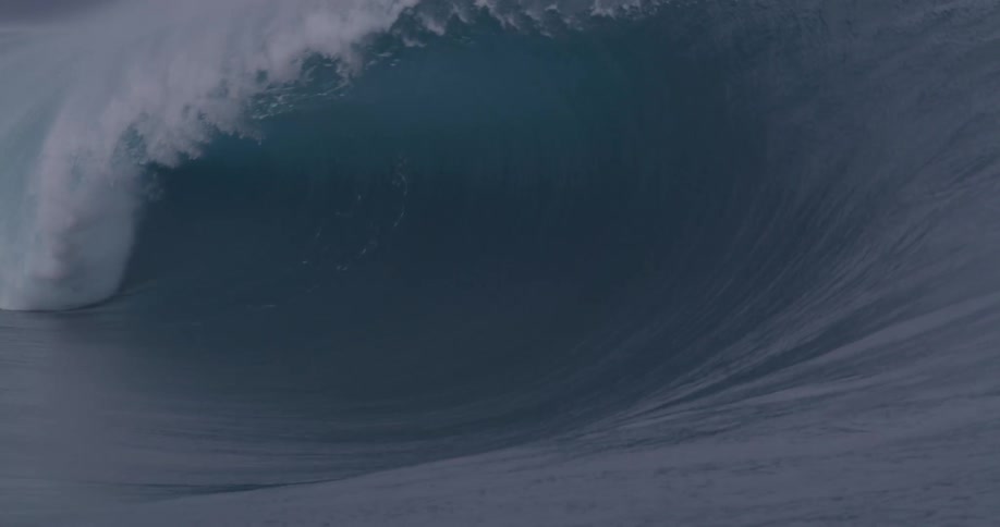 Surfers ride a large tubular wave