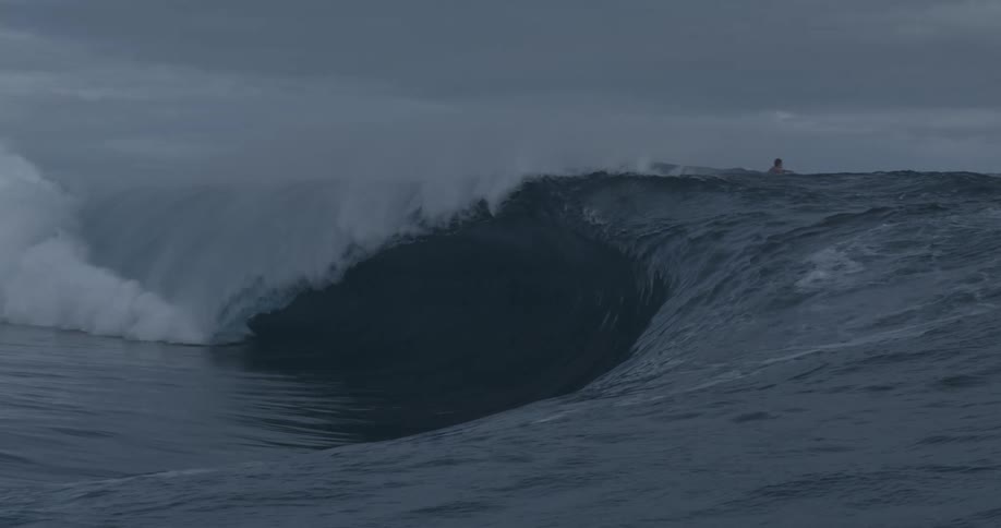 A large wave crashes by the surfers