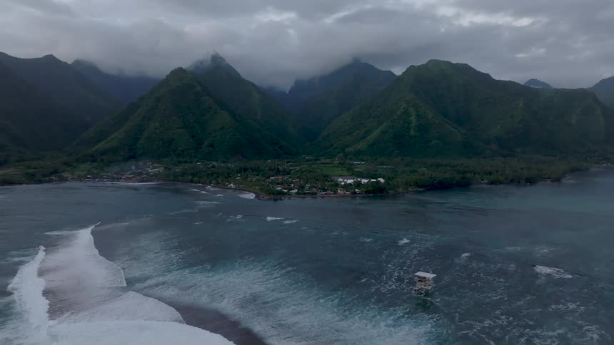 Aerial view of a beach with gigantic mountains on the horizon