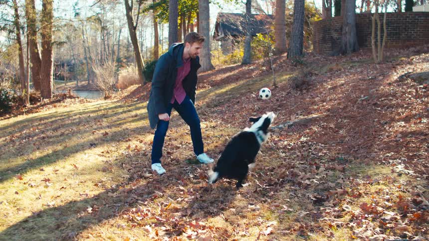 A man is playing with a ball with his dog