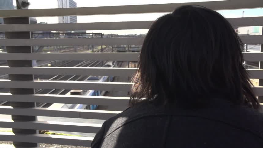 A person looks through a fence at a moving train below