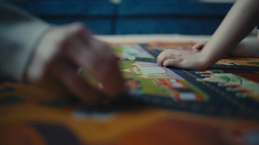Little boy playing with toy cars on a play mat and his mom playing with him