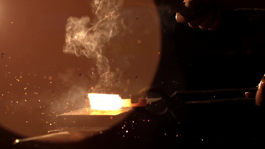 A footage of a blacksmith focused while forging an iron