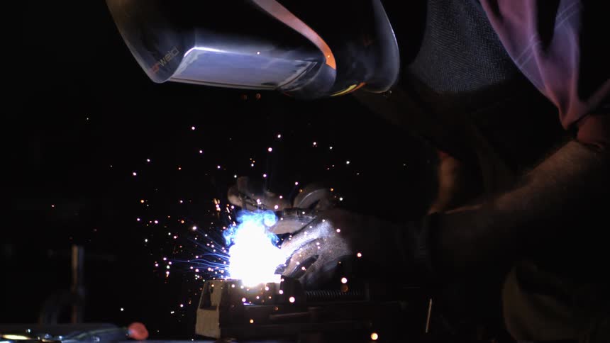 Person is welding a piece of metal with visible sparks